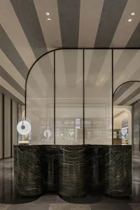 Modern lobby with glass partition and curved edges, featuring sleek design and sophisticated materials.