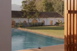Modern residential property featuring a swimming pool, green lawn, and stone and wood architecture.