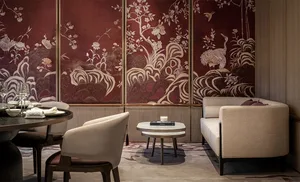 A modern restaurant interior featuring white chairs, a beige sofa, and a round dining table set with plates, glasses, and tow