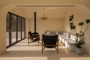 A living room with a neutral color palette, featuring minimalist furniture and a modern fireplace.