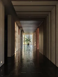 Long, illuminated corridor featuring granite walls and floor, with a potted plant at the far end.