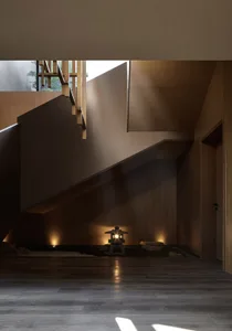 Modern entryway featuring a wooden staircase with a lantern and rocks