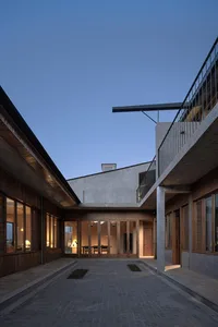 A modern residential interior featuring a courtyard with concrete walls and floor, illuminated by warm lights.
