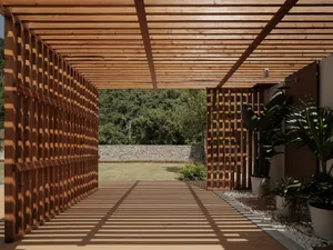 A modern wooden patio garden space featuring lattice walls, greenery, and a stone wall in the background.