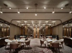 Industrial-style restaurant interior with metal and glass elements, featuring round tables, modern seating, and minimalist de