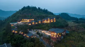 Modern residential buildings with lights on, situated on a hillside.