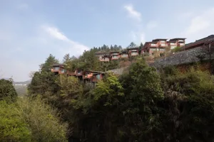 Multiple residential houses built into a hillside, surrounded by trees and vegetation.