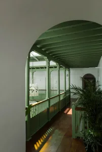一條流線工業風走廊，設有綠意陽台與木質地板。
