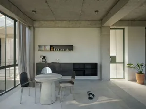 A minimalist residential kitchen featuring concrete finishes and a concrete dining table.