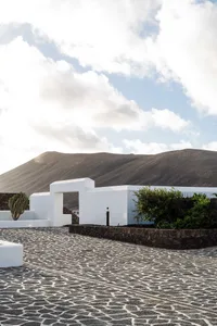 Concrete path with white minimalist structures and dark hills in the background.