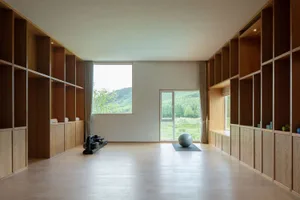 Spacious workout room with wooden walls and floor, featuring a stationary rowing machine and an exercise ball on a mat.