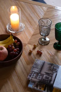 A modern coffee table featuring wooden furniture, a candle, a bowl of fruit, and a stack of books.