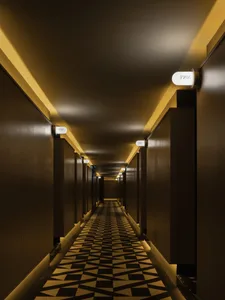 Modern corridor with metallic walls and yellow lighting.