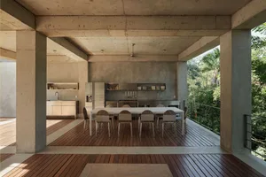 Modern dining room with concrete exterior and steel and wooden furniture.