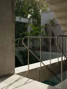 Modern architectural design featuring a concrete and glass exterior with greenery in the background.