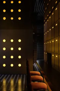 Modern hotel lobby interior with metal wall panels, wooden furniture, and warm yellow lights.