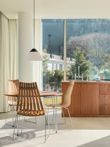 Modern kitchen featuring wooden furniture and large windows with a view of trees.