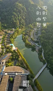 Aerial view of residential houses and buildings surrounded by lush greenery and a meandering river.