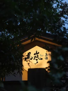 A illuminated Chinese signage on the facade of a traditional Japanese tea house.