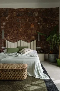 Minimalist bedroom with linen, woven rattan, and stone wall