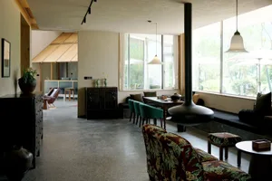 A minimalist living room with concrete floors, modern furniture, and large windows.