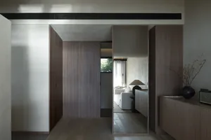Modern minimalist living room with white walls, wood paneling, and a white sofa.
