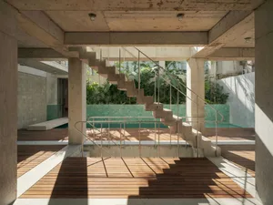 A minimalist staircase with concrete steps and steel railings adjacent to a swimming pool, set against a backdrop of green fo
