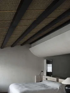 Interior of a modern minimalist bedroom featuring a concrete finish and a view of the ocean through a window.