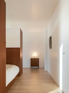 Modern minimalist bedroom featuring wooden furniture and a warm, cozy atmosphere.