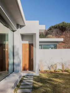 Modern minimalist house with concrete exterior and wooden door.
