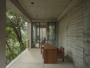 Concrete patio with minimalist furniture and lush greenery surrounding it.