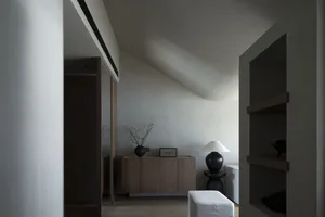 A modern minimalist living room with light-colored wood furniture and concrete accents.