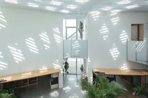 A modern office space featuring wooden tables and concrete walls.