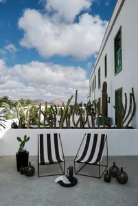 Modern patio with black and white striped chairs, concrete walls, and greenery.