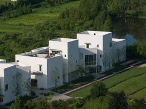 Modern residential building with white concrete exterior and large glass windows.