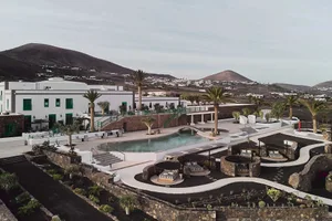 Modern resort hotel featuring a minimalist pool area with concrete, glass, and palm trees.