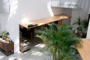 A modern restaurant interior with wooden tables and green plants.