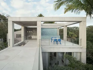 A modern rooftop deck made of concrete with a concrete wall and a blue table and chairs.