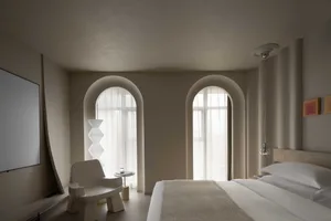 A minimalist bedroom with beige and white furniture and a neutral color palette.