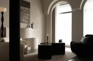 A modern living room with minimalist furniture, white walls, and large windows.