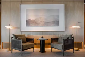 A minimalist lobby featuring wooden furniture, fabric upholstery, and glass accents.