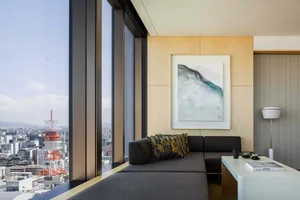 Modern living room featuring a city view with a large artwork on the wall and a dark sectional sofa.