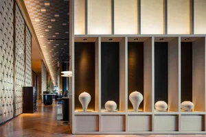 Modern hotel corridor featuring concrete and wooden flooring with illuminated lighting.