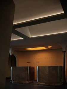 Modern hotel lobby with a reception counter made of polished marble, featuring elegant curved lighting fixtures and a warm, i