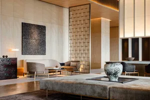 A modern living room featuring beige upholstered furniture, wooden paneling, and metallic accents.