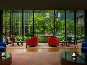 Indoor lounge area with modern furniture, large windows, and green outdoor garden.