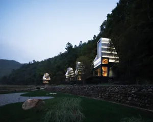Modern luxury cabin with glass and concrete architecture surrounded by nature.
