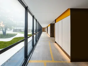 Modern office corridor interior with concrete, glass, and steel materials.