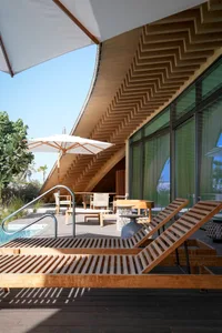 A modern patio with a swimming pool and wooden furniture and stairs.