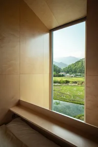 Wood-paneled wall with a window overlooking a lush green landscape.
